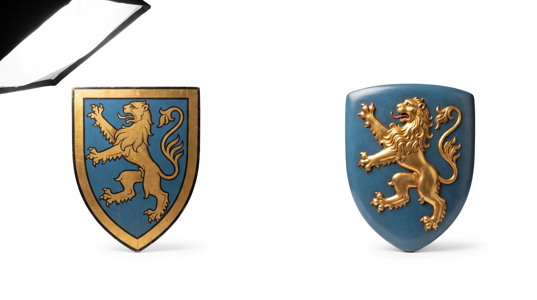 Two hand-painted shields carrying the same gold lion on a blue field, one painted in a fifteenth-century Flemish manner and one in a nineteenth-century revival manner