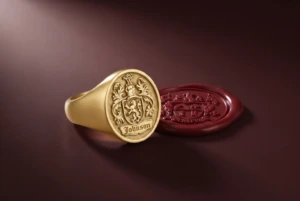 A women’s gold signet ring and a red wax seal impression on a deep oxblood ground